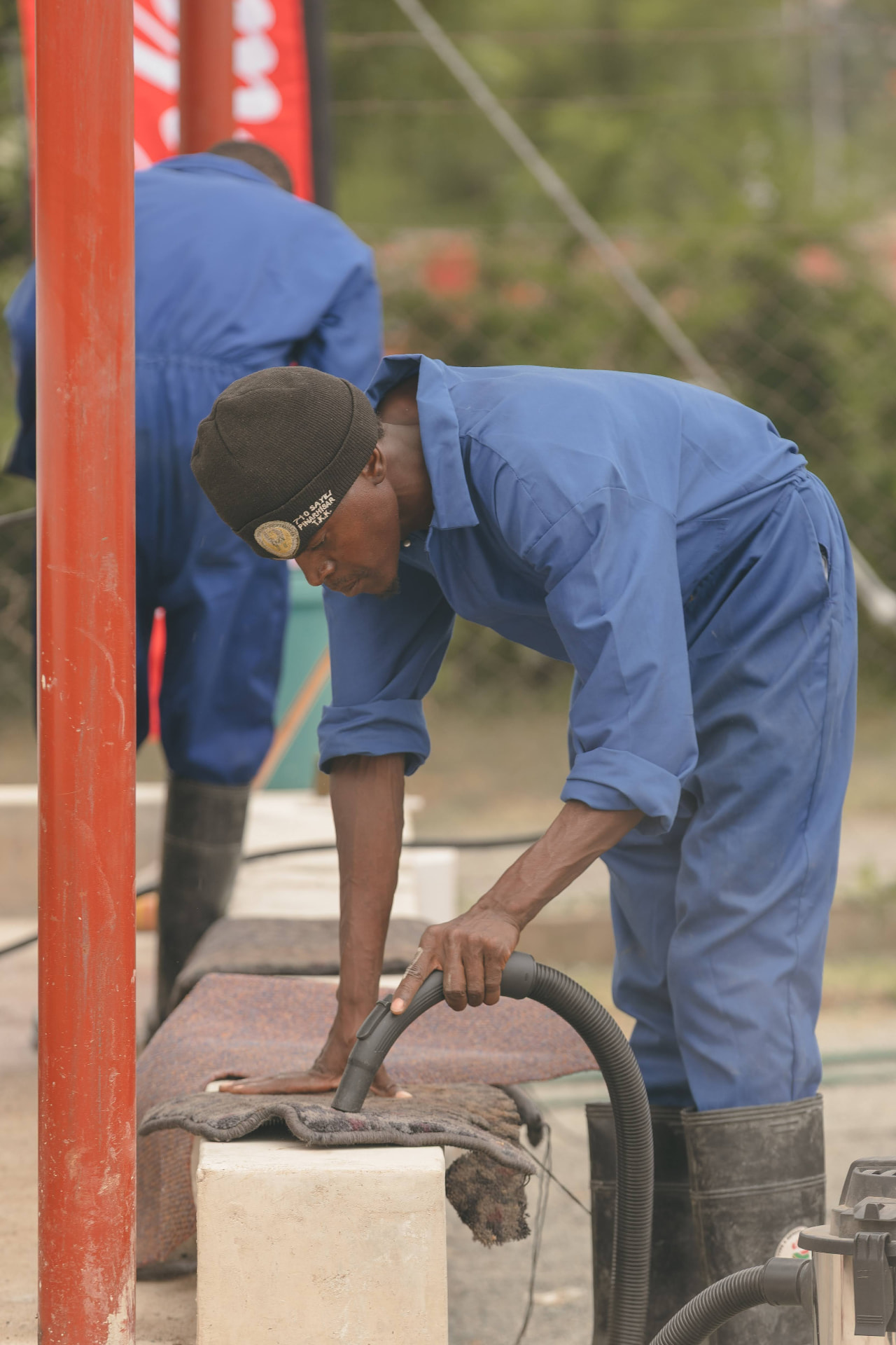 A MAPS Village attendant vacuuming car mats on the wash bay