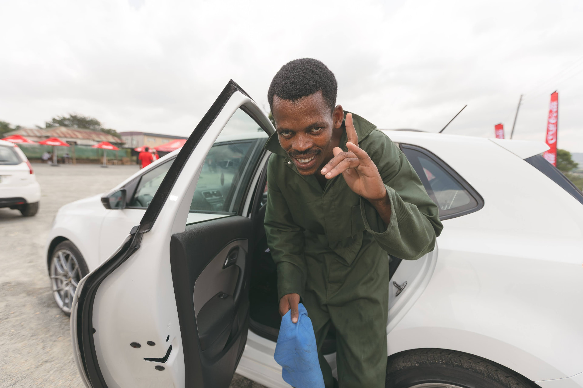 A MAPS Village team member smiling beside a freshly cleaned car